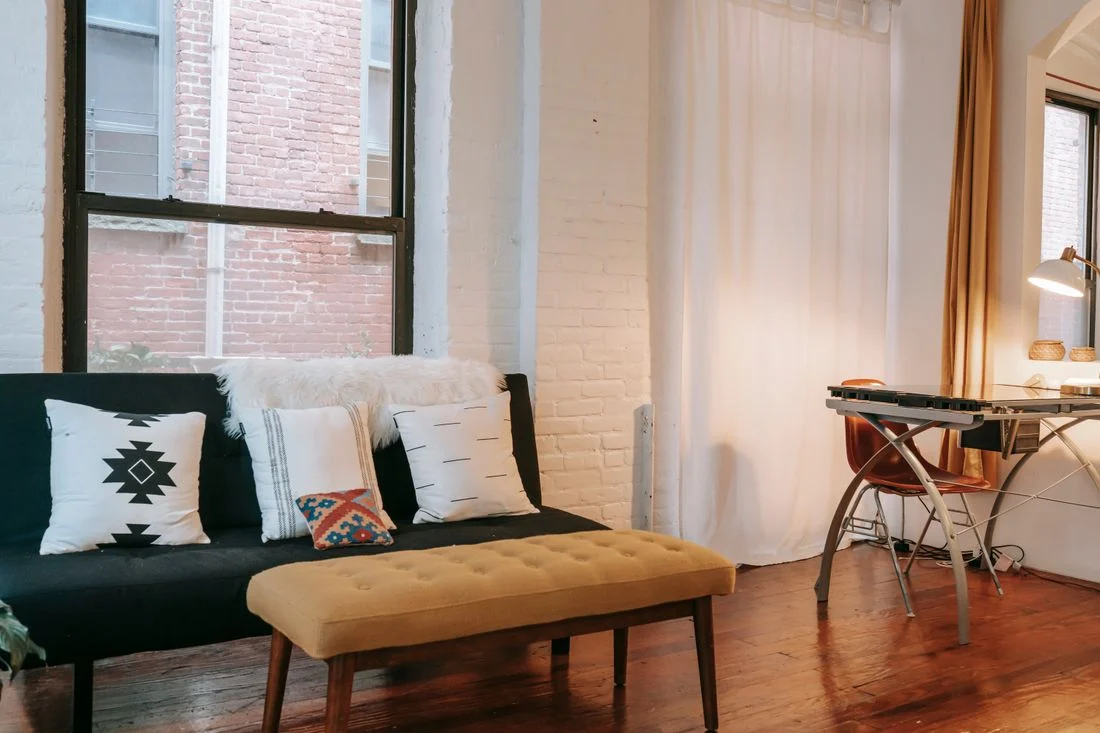 Upholstered bench in front of a sofa near a window