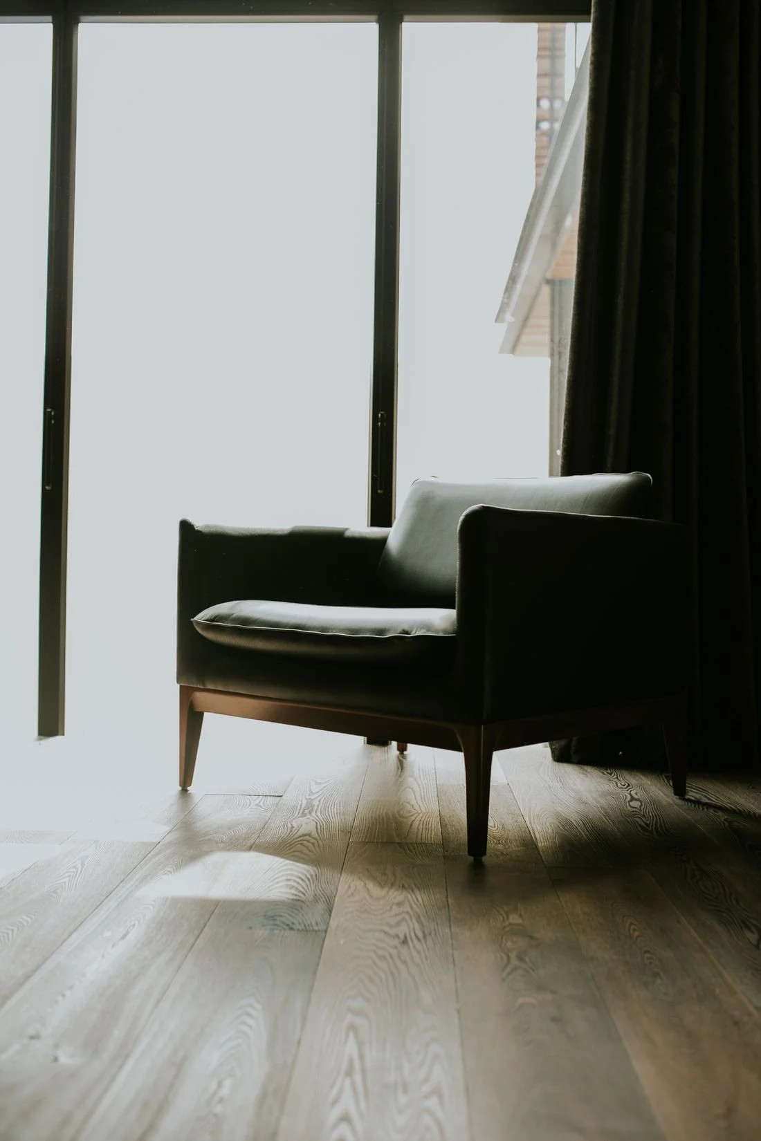 Dark armchair beside a tall window