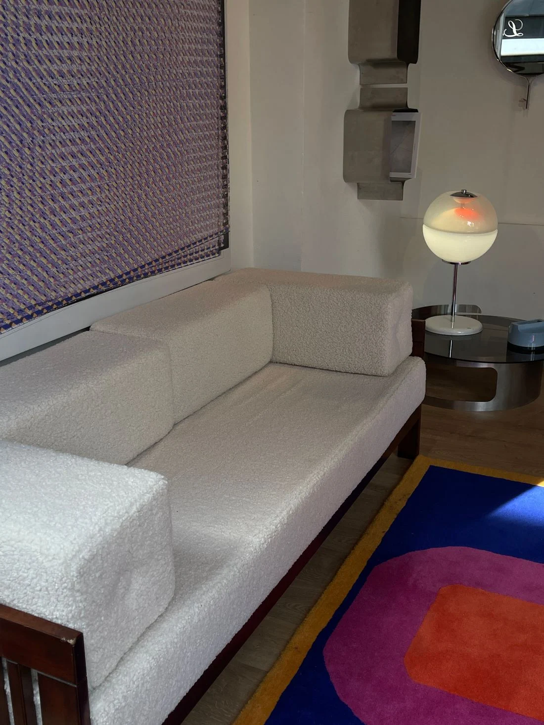Long pale sofa with colorful rug and simple furnishings