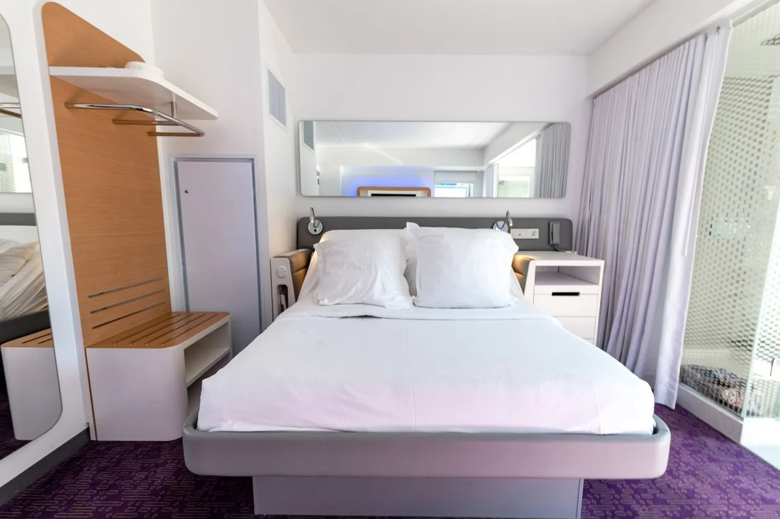 Compact bedroom with a white bed and light furnishings