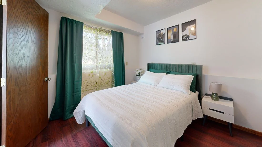 Bed with a green headboard against a light wall