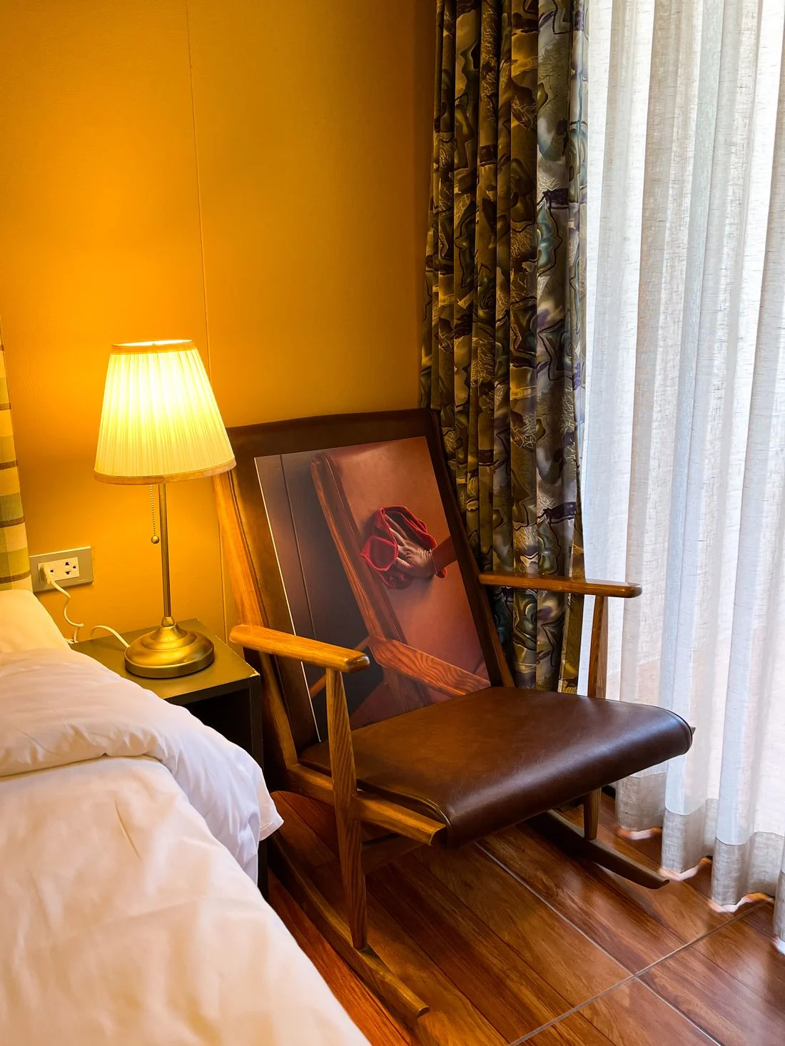 Wooden reading chair and lamp beside bedroom curtains