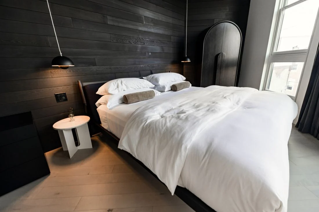 Bedroom with dark wood wall panels and white bedding