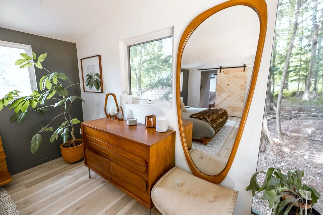 Wooden dresser below a large oval mirror