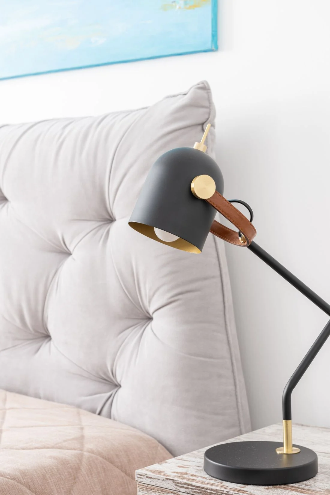 Adjustable bedside lamp beside a tufted headboard